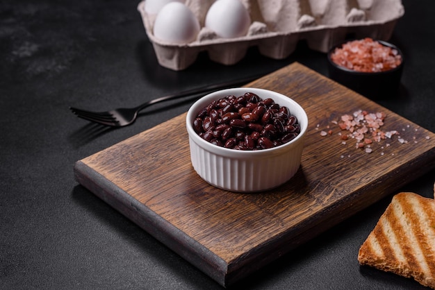 Black canned beans in a white saucer against a dark concrete background