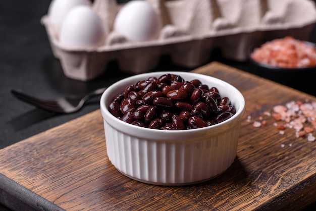 Black canned beans in a white saucer against a dark concrete background