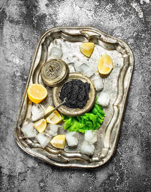 black caviar on the old tray of ice. On rustic background .