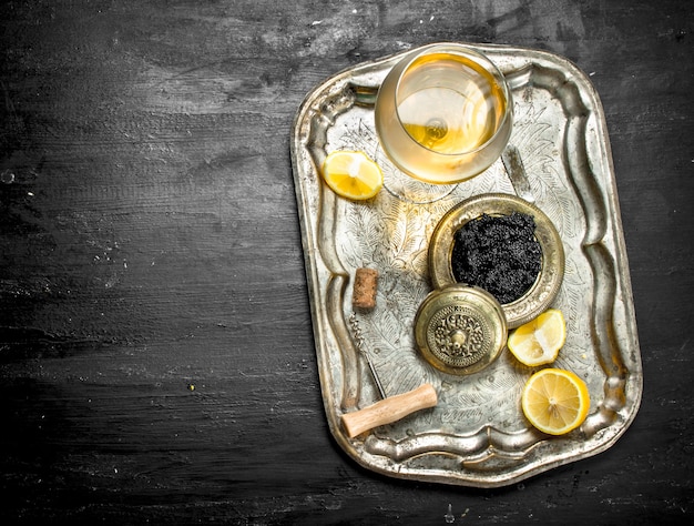 Black caviar with white wine on the old tray.