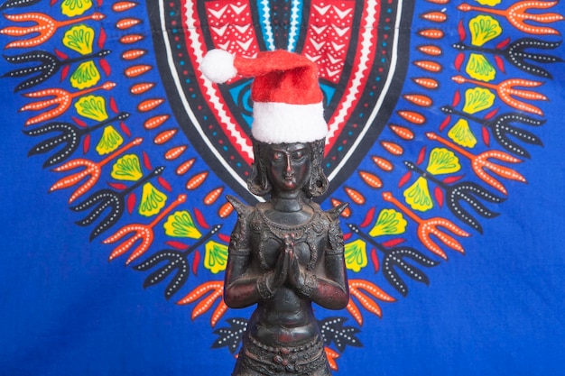 Black ceramic figure of kneeling young Buddha in a christmas hat