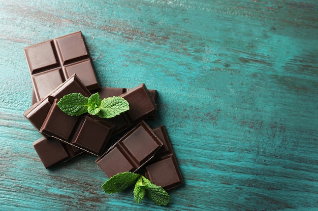 Black chocolate pieces on color wooden surface