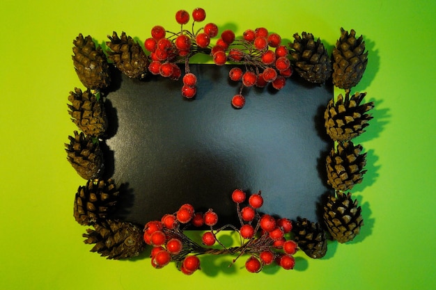 Black Christmas frame made of cones and red berries Place for an inscription Flat design Winter and christmas