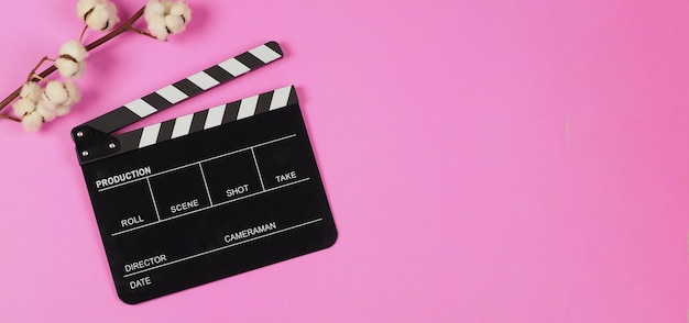 Black Clapper board and cotton flowers on pink background