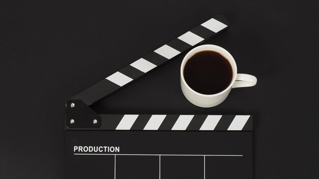 Black Clapper board and hot coffee white cup on black background.