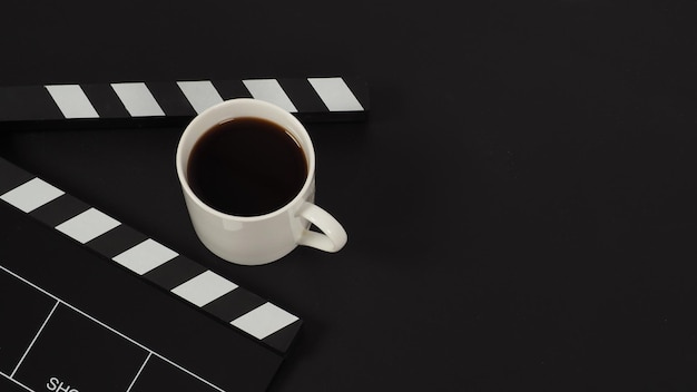 Black Clapper board and hot coffee white cup on black background