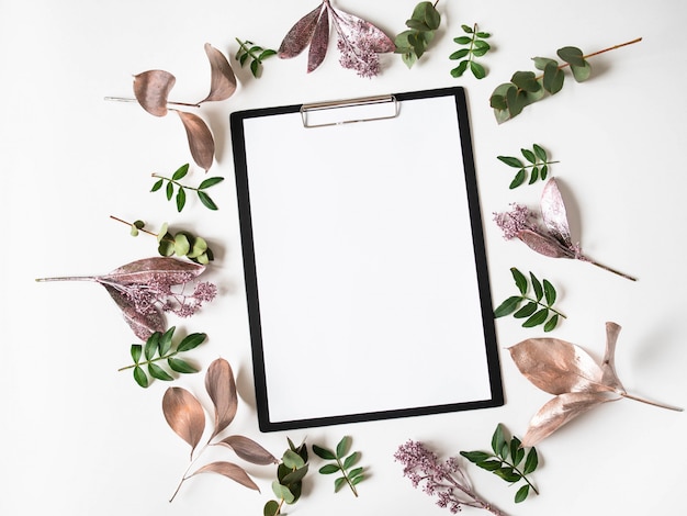 Black clipboard, white paper for text and creative frame composition of various painted leaves