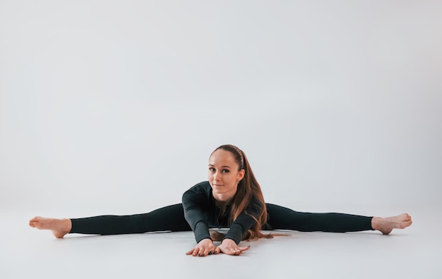 In black clothes Young woman in sportive clothes doing gymnastics indoors