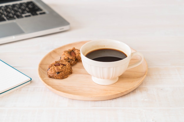 black coffee and cookies with laptop and note book