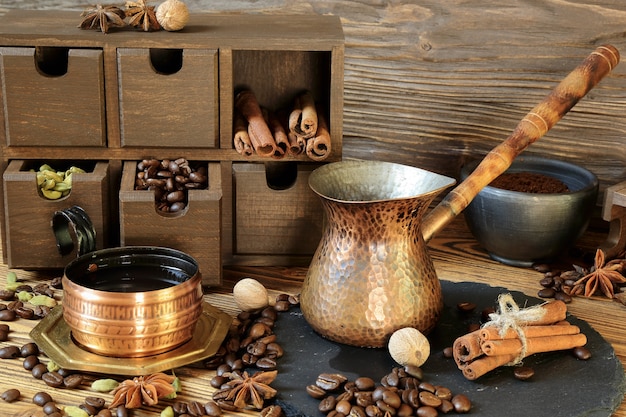 Black coffee in a copper cup and spices on a wooden table