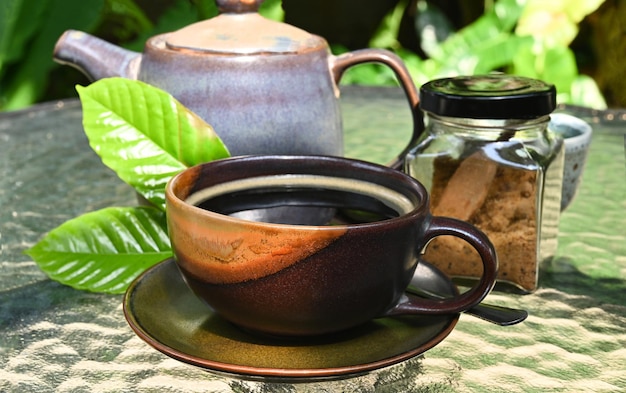 Black coffee cup on the table glass with tea jar coffee leaves seems relaxed mood in garden