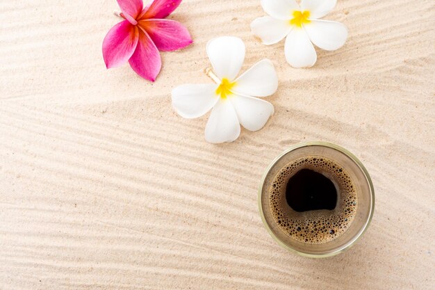 Black Coffee In Double Wall Glass On sand Beach Next To Frangipani Flowers