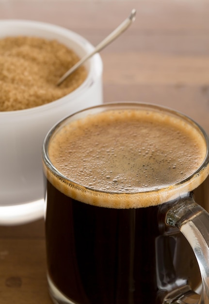 Black coffee and froth in glass mug with sugar