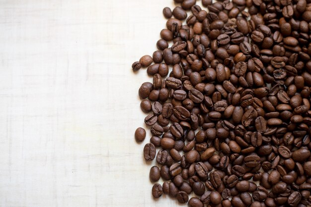 Black coffee grains lie on light wooden table, background image. place for text