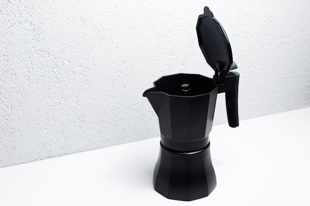 Black coffee moka pot, on white surface.