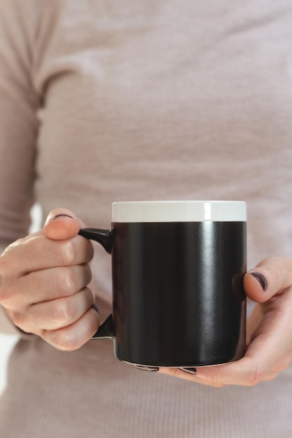 Black coffee mug mockup for design demonstration stylish cup mock up in female hands