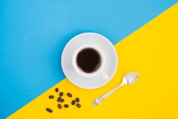 Black coffee in the white cup and coffee beans on the two-color.