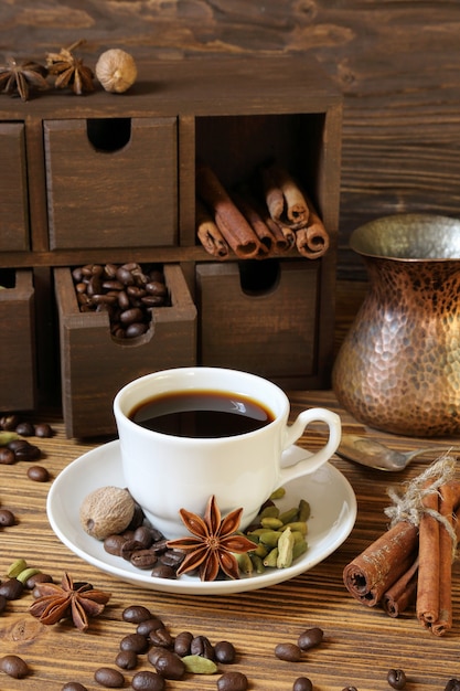 Black coffee in a white cup and spices on a wooden table