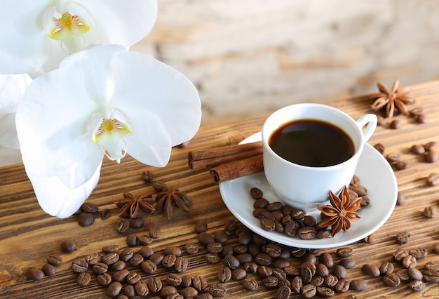 Black coffee with cinnamon on stone wall and orchids