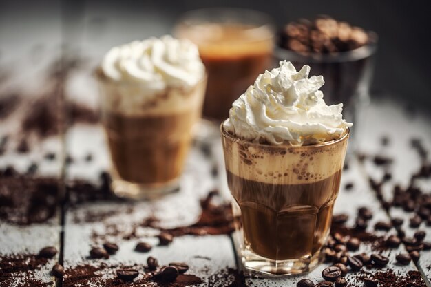 Photo black coffee with whipped cream in glass cups and spilled coffee beans.