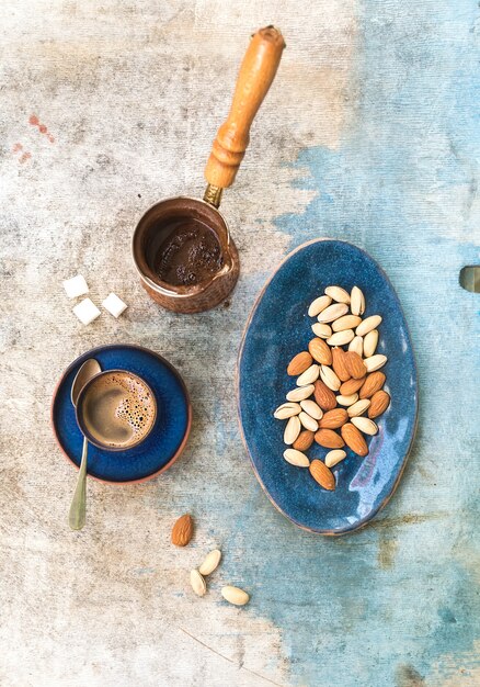 Black coffeee with almonds and pistachios over light blue table. Top view