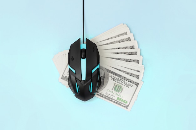 Black computer mouse on many hundred dollar bills