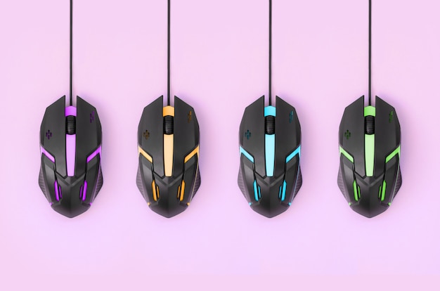 Black computer mouses hang on pastel pink background