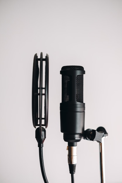 Black condenser microphone on stand with pop filter