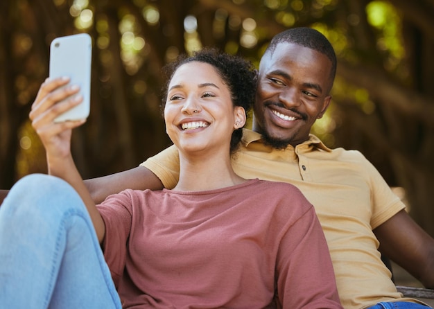 Black couple phone and selfie with smile at outdoor nature park for travel happiness and social media profile picture content update Happy man and woman with 5g network connection on vacation date