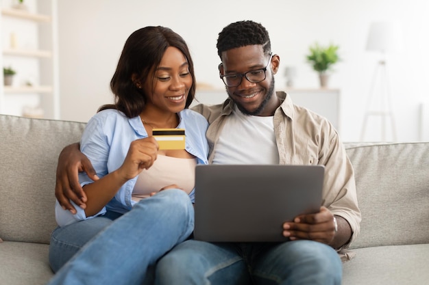 Black couple using pc and debit credit card at home