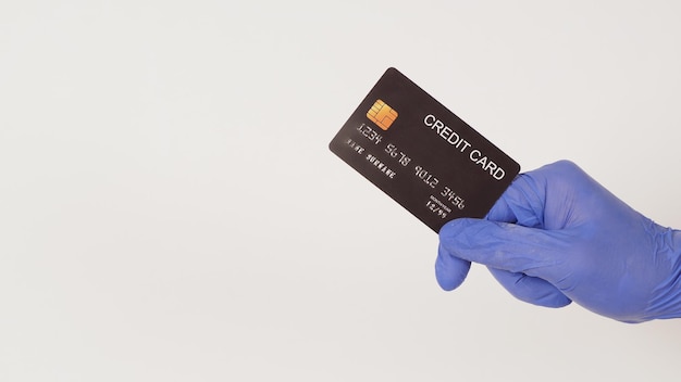 A black credit card in hand and wear violet or purple latex glove isolated on white background