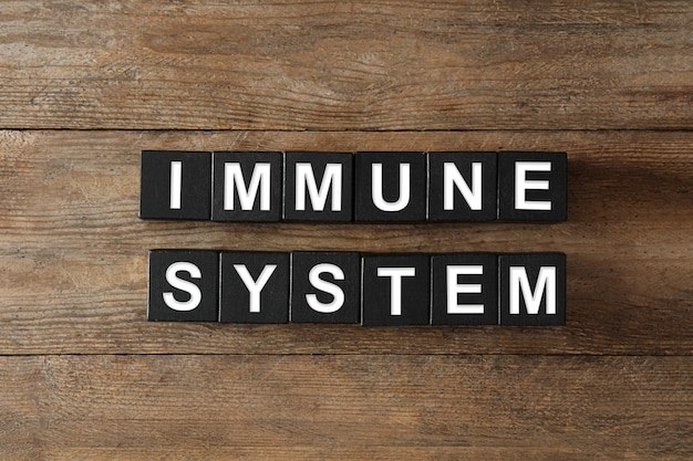 Black cubes with phrase Immune System on wooden table flat lay