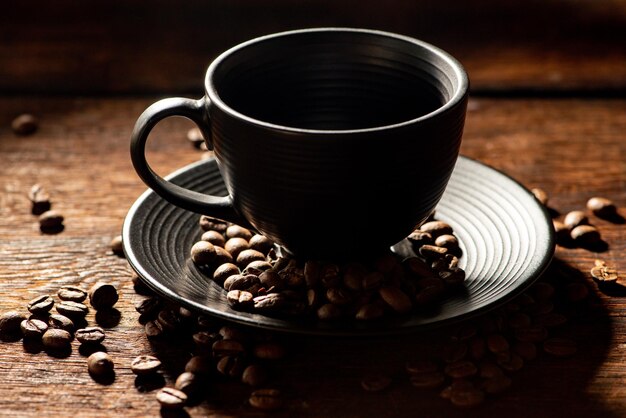 Black cup black cup with coffee beans next to it on rustic wood dark food style photo selective focus