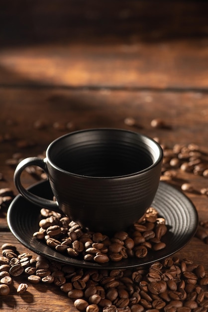 Black cup black cup with coffee beans next to it on rustic wood dark food style photo selective focus