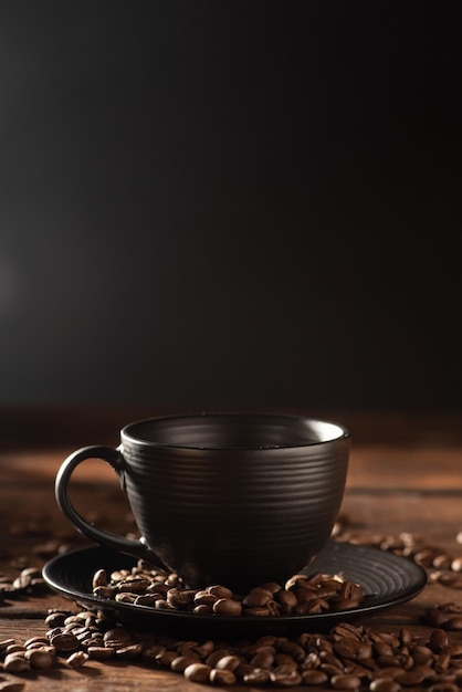 Black cup black cup with coffee beans next to it on rustic wood dark food style photo selective focus