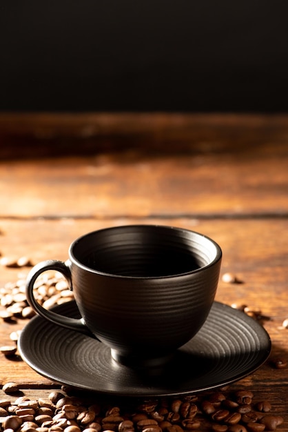 Black cup black cup with coffee beans next to it on rustic wood dark food style photo selective focus