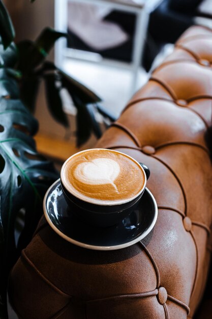 Black cup of cappuccino with latte art on wooden background Beautiful foam