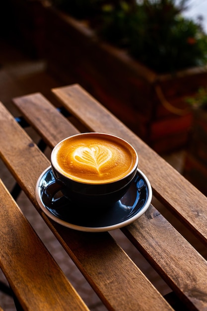 Black cup of cappuccino with latte art on wooden background