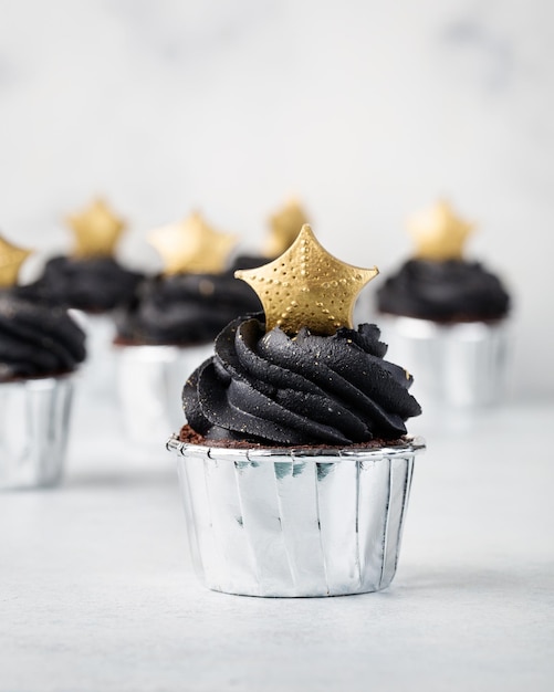 Black cupcakes decorated with a gold star on a light background