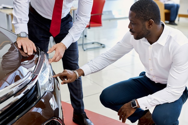 Black customer man asks questions about headlights of car in dealership