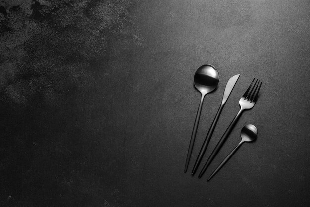 Black cutlery on a concrete dark table. Dining table preparation