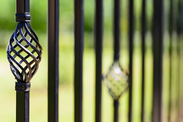 Black decorative metal fence, angular iron rods and curved upper part. 