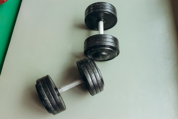 Black desk of free space for your decoration and blurred gym interiorMetal dumbbells and fit life