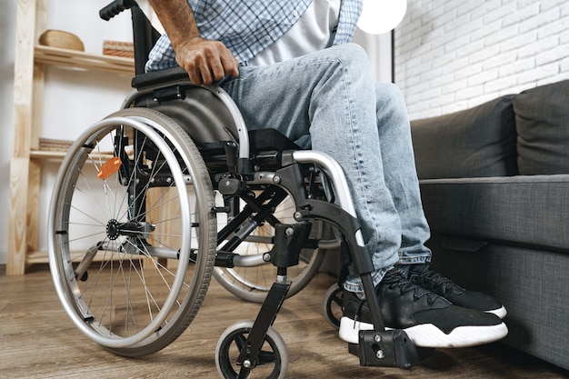 Black disabled man sits down on wheelchair at home