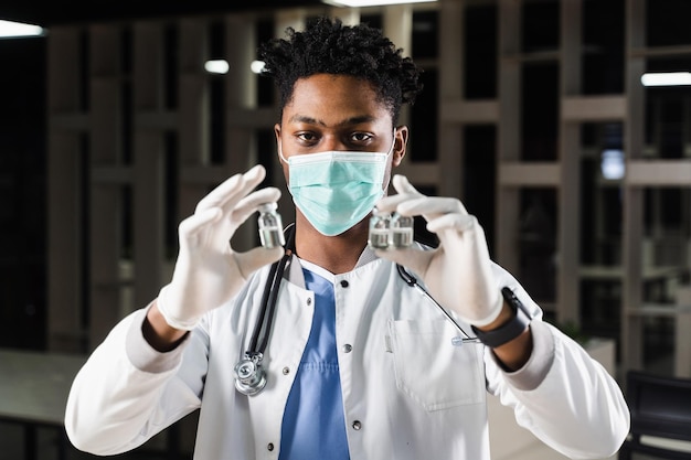 Black doctor with 3 doses of vaccine Booster vaccination African doctor in medical mask is holding vaccines in hand