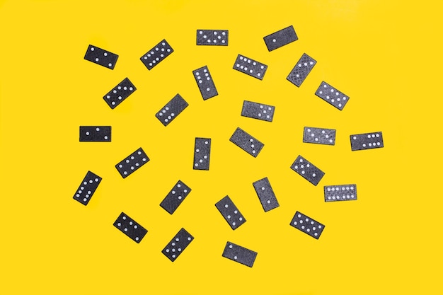 Black domino pieces on a yellow background in a top view