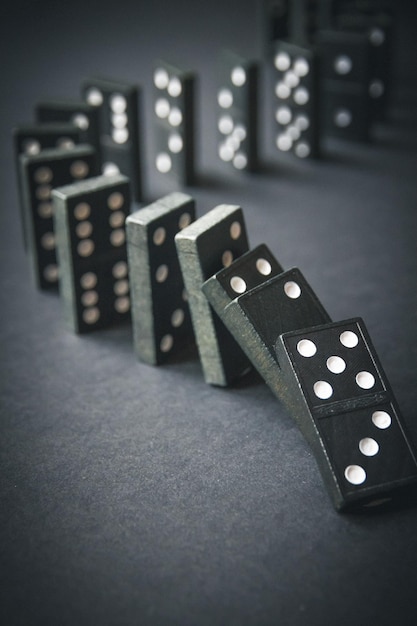 Black dominoes chain on dark table background