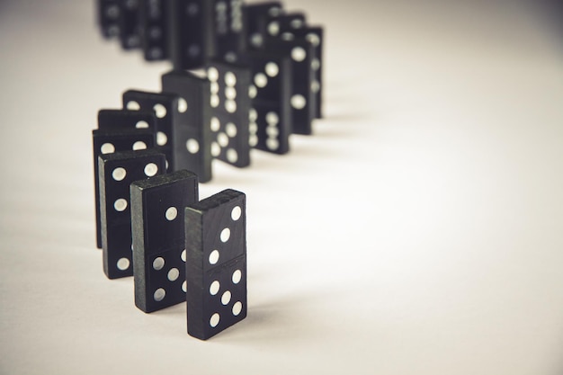 Black dominoes chain on white table background