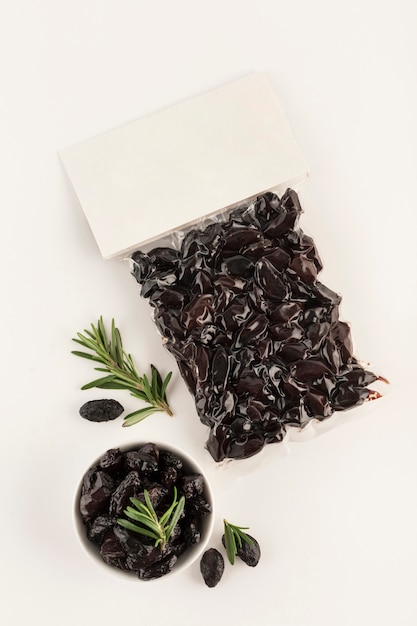 Black dried olives in vacuum packaging with a place for the label on a light background. Top view with a copy space for text. Vertical orientation.