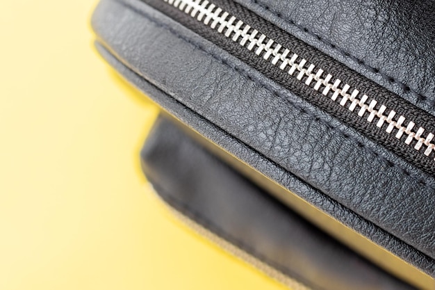 Black eco leather backpack with zipper closeup on yellow background selective focus